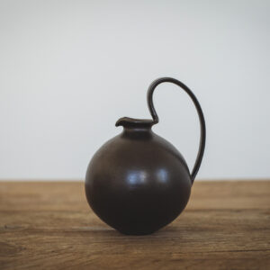 Black flagon shaped jug/vase with large looped handle. Matt black finish // Jwg / fâs siâp fflag du gyda handlen fawr, dolennog. Gorffeniad du Matt