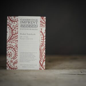 A red and white paisley patterned notebook. Photographed on a rustic wooden table against a 