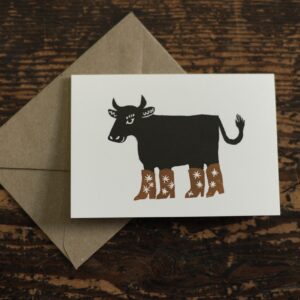 lino cut print of a cow wearing star patterned boots