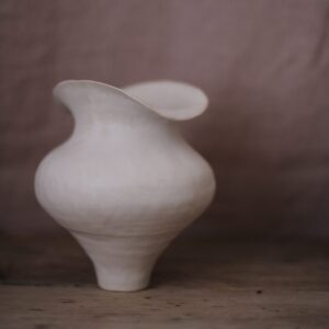 white bulbous vase on a plaster pink background 