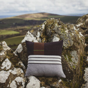 Dark and light blue striped cushion shown against a craggy Welsh hillside
