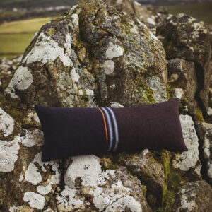 Long, bolster style dark blue cushion, photographed against a craggy welsh hillside