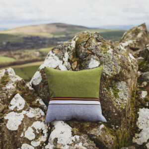 Green and sky blue coloured cushion, photographed outside against the craggy welsh hills