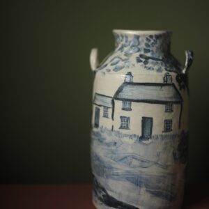 white and blue hand painted ceramic milk churn showing a traditional welsh cottage.