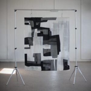 A black and white square textile piece. Made up of geometric shapes. 
